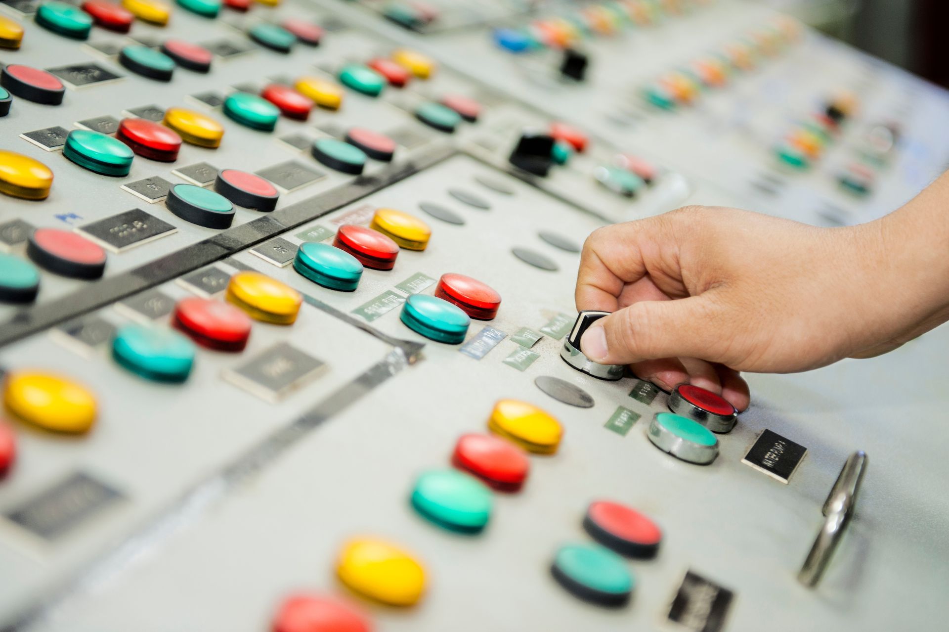 Hand turning a knob on a control panel with colorful buttons and switches. Hand turning a knob on a control panel with colorful buttons and switches.