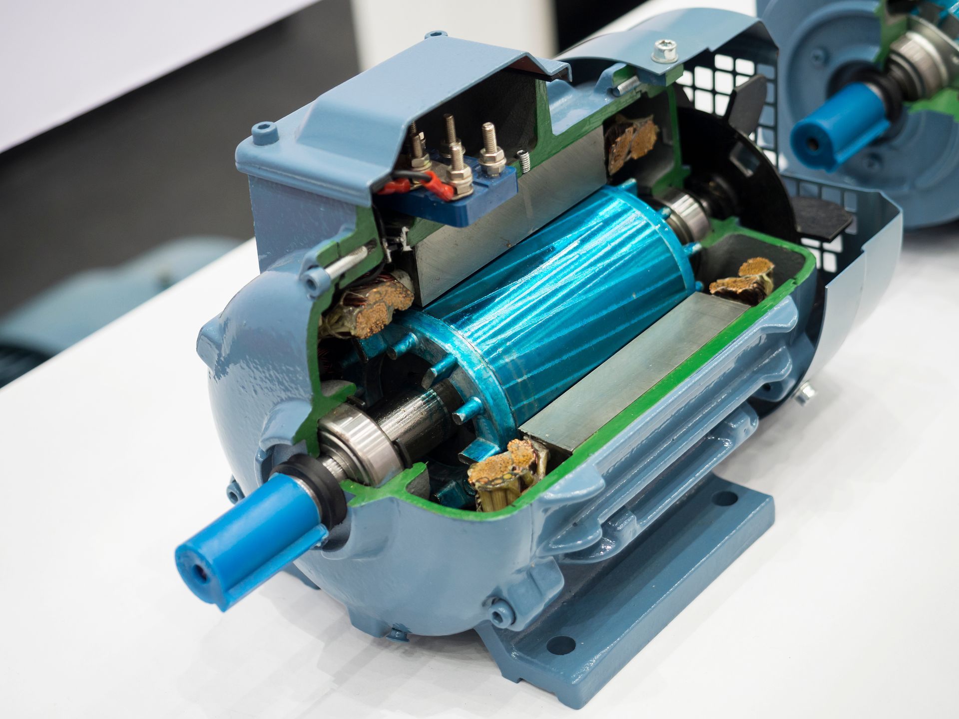 Cutaway view of a blue electric motor showing copper windings and internal components. Cutaway view of a blue electric motor showing copper windings and internal components.