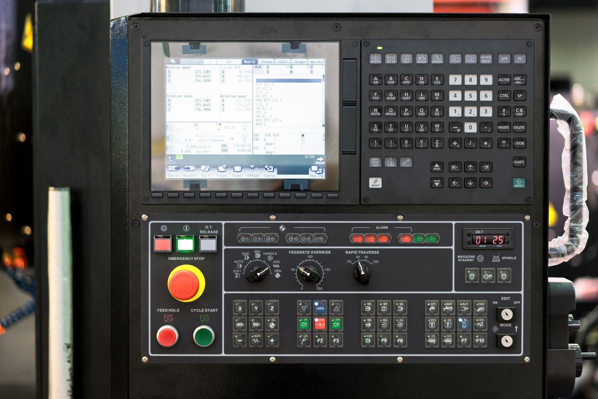 Industrial machine control panel with screen, keypad, buttons, and knobs in a workshop. Industrial machine control panel with screen, keypad, buttons, and knobs in a workshop.
