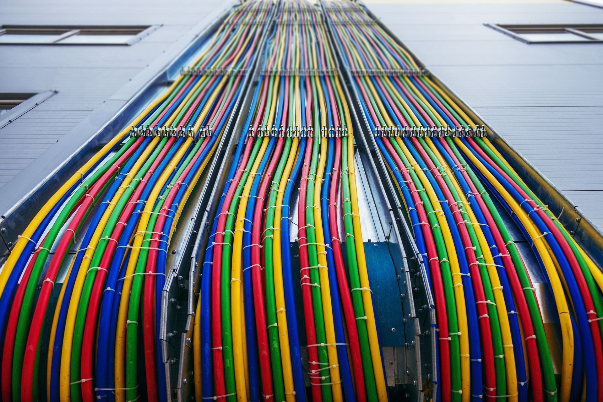 Colorful cables running up a building wall into a rooftop conduit opening. Colorful cables running up a building wall into a rooftop conduit opening.