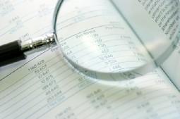 A magnifying glass is sitting on top of a notebook next to a pen.