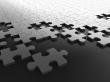 A black and white photo of a bunch of puzzle pieces on a table.