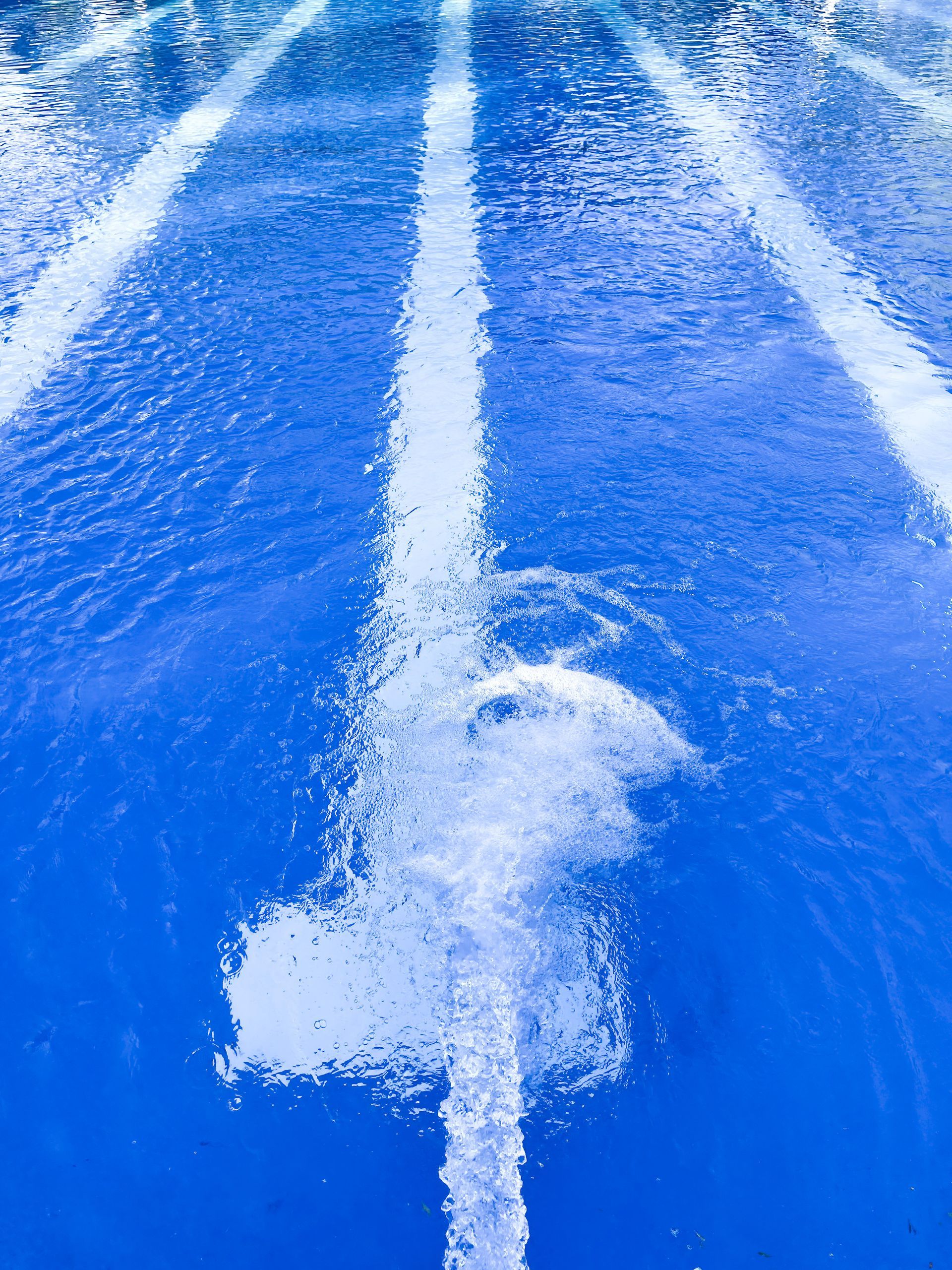 Blue running track with white lane lines and scuffed surface Blue running track with white lane lines and scuffed surface