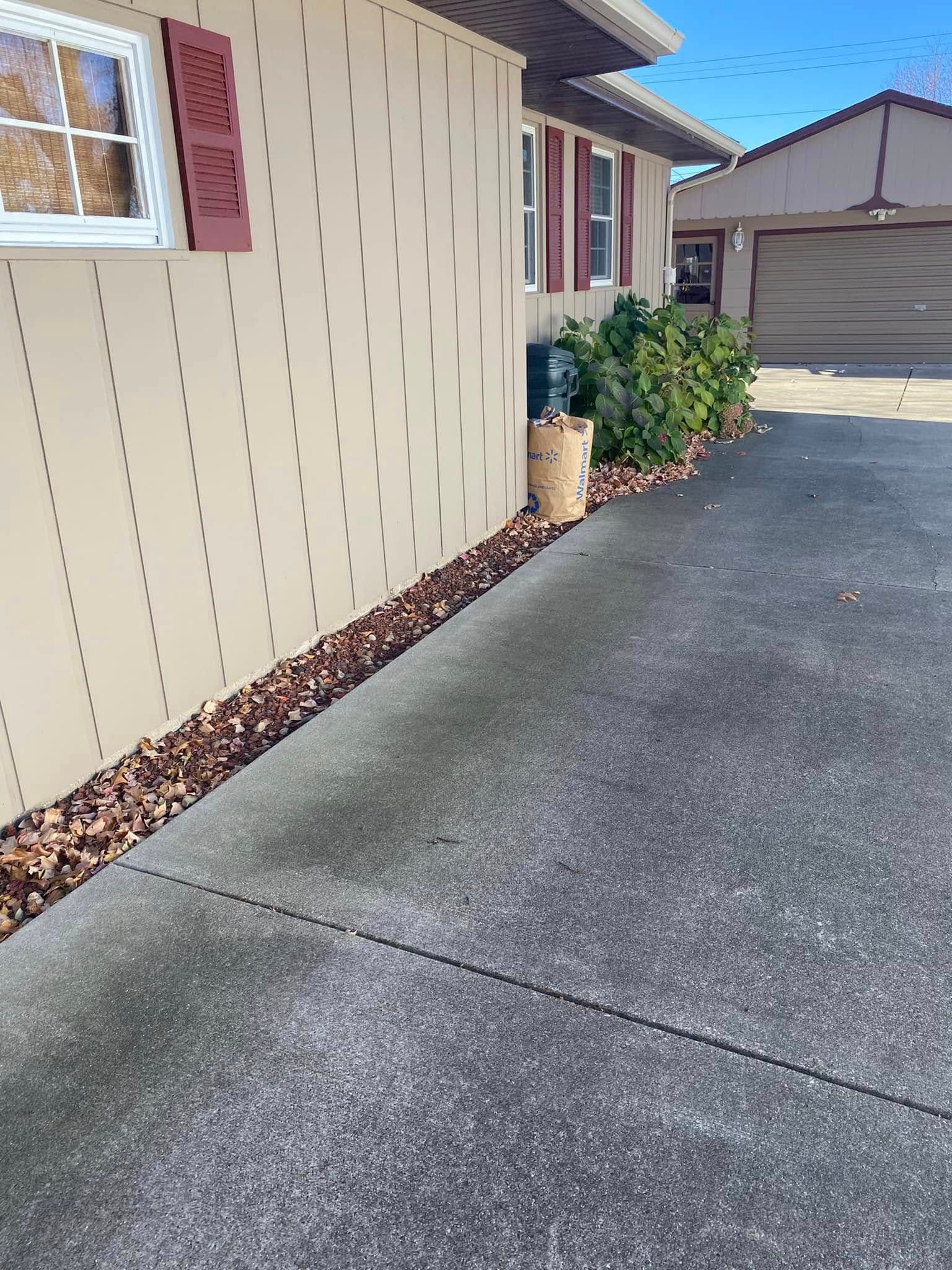 Side yard walkway beside a beige house, leading to a garage with potted plants along the wall.