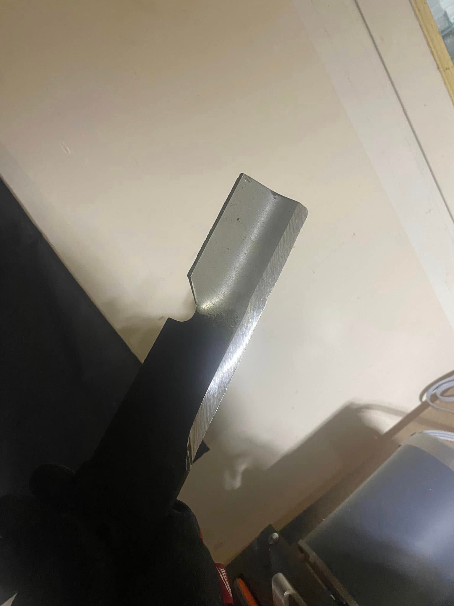 Close-up of a black-and-silver vacuum cleaner head against a white wall and floor.