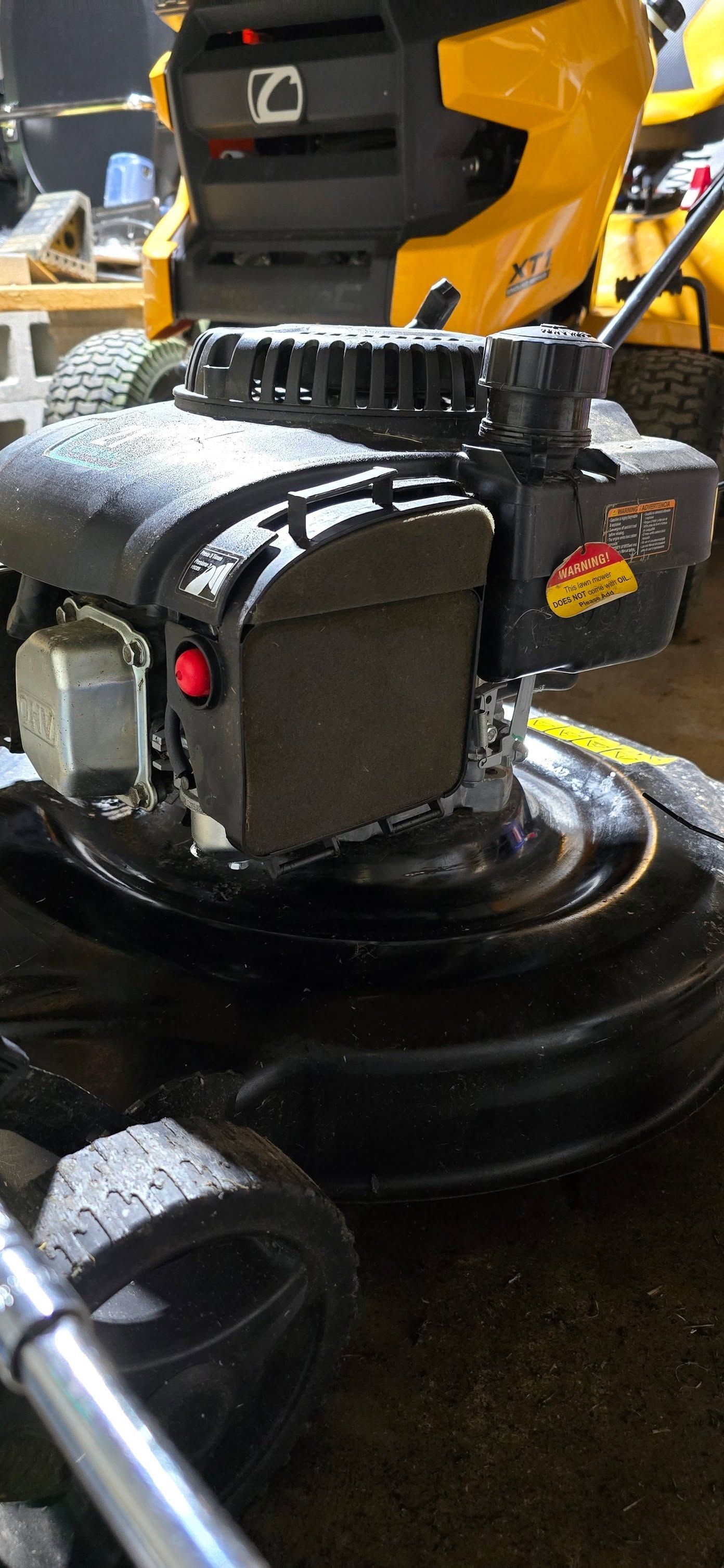 Close-up of a yellow-and-black lawn mower deck with wet grass clippings on the housing.