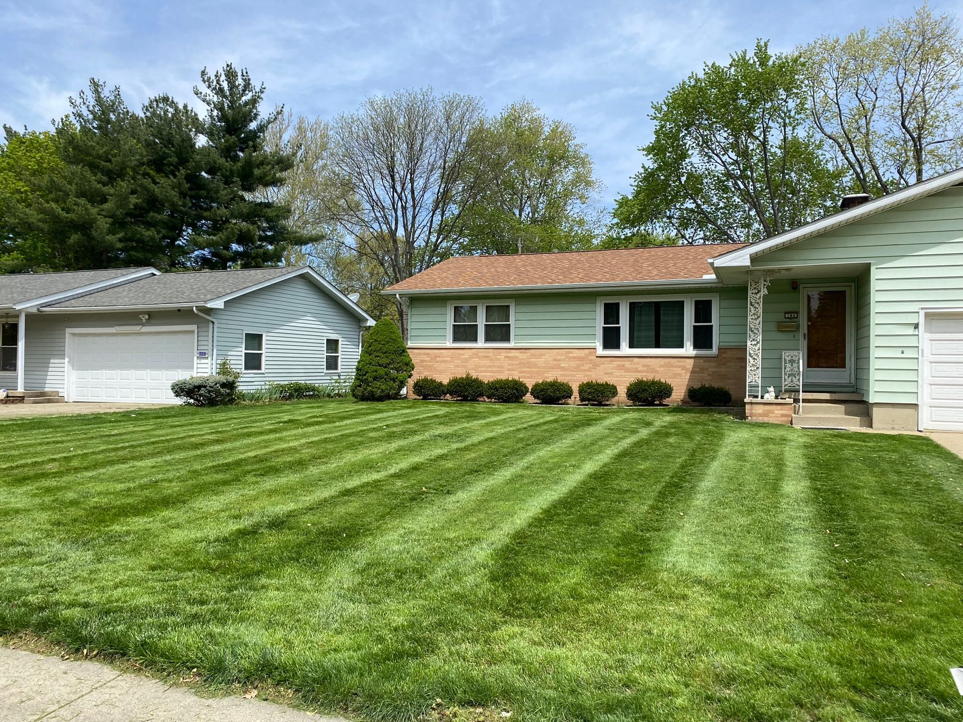 Suburban homes with a freshly mowed green lawn and clear blue sky