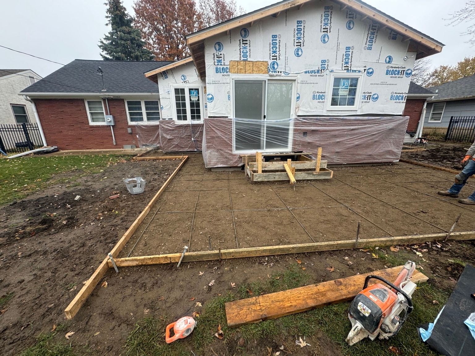 House under construction with exposed insulation, dirt yard, and wooden forms for a concrete patio and walkway
