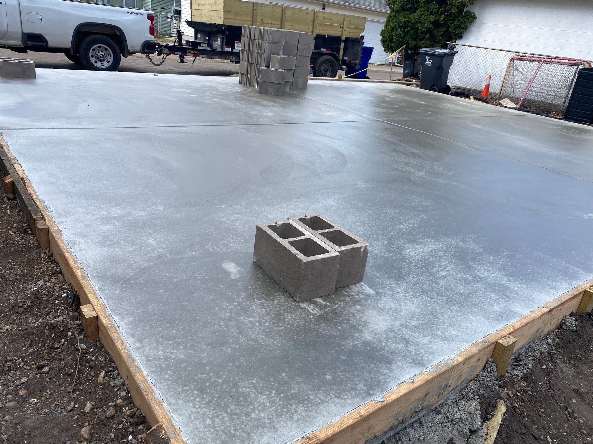 Fresh concrete foundation slab with a cinder block in the foreground at a construction site