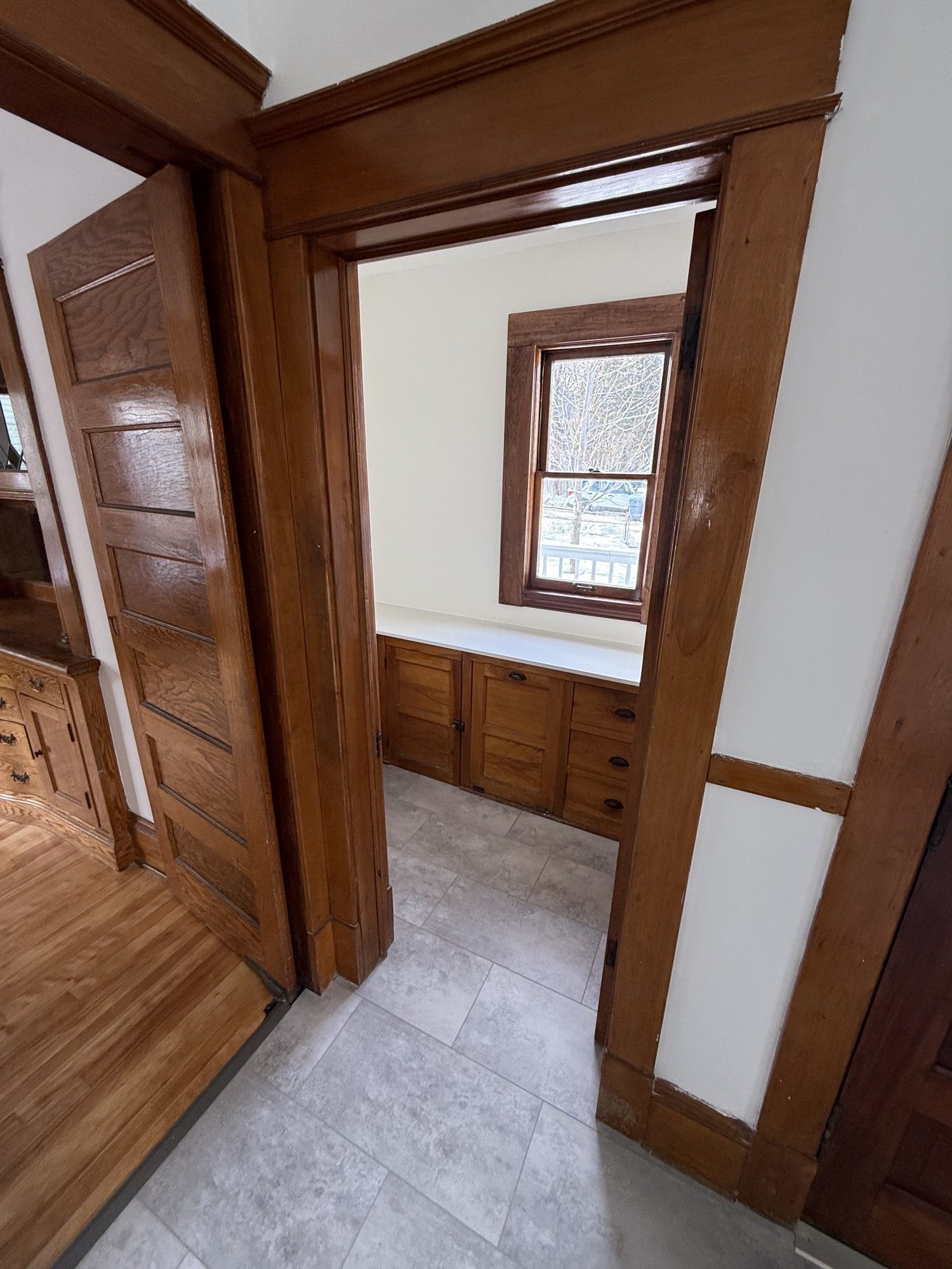 Wood-paneled hallway with a small window seat nook and gray tiled floor