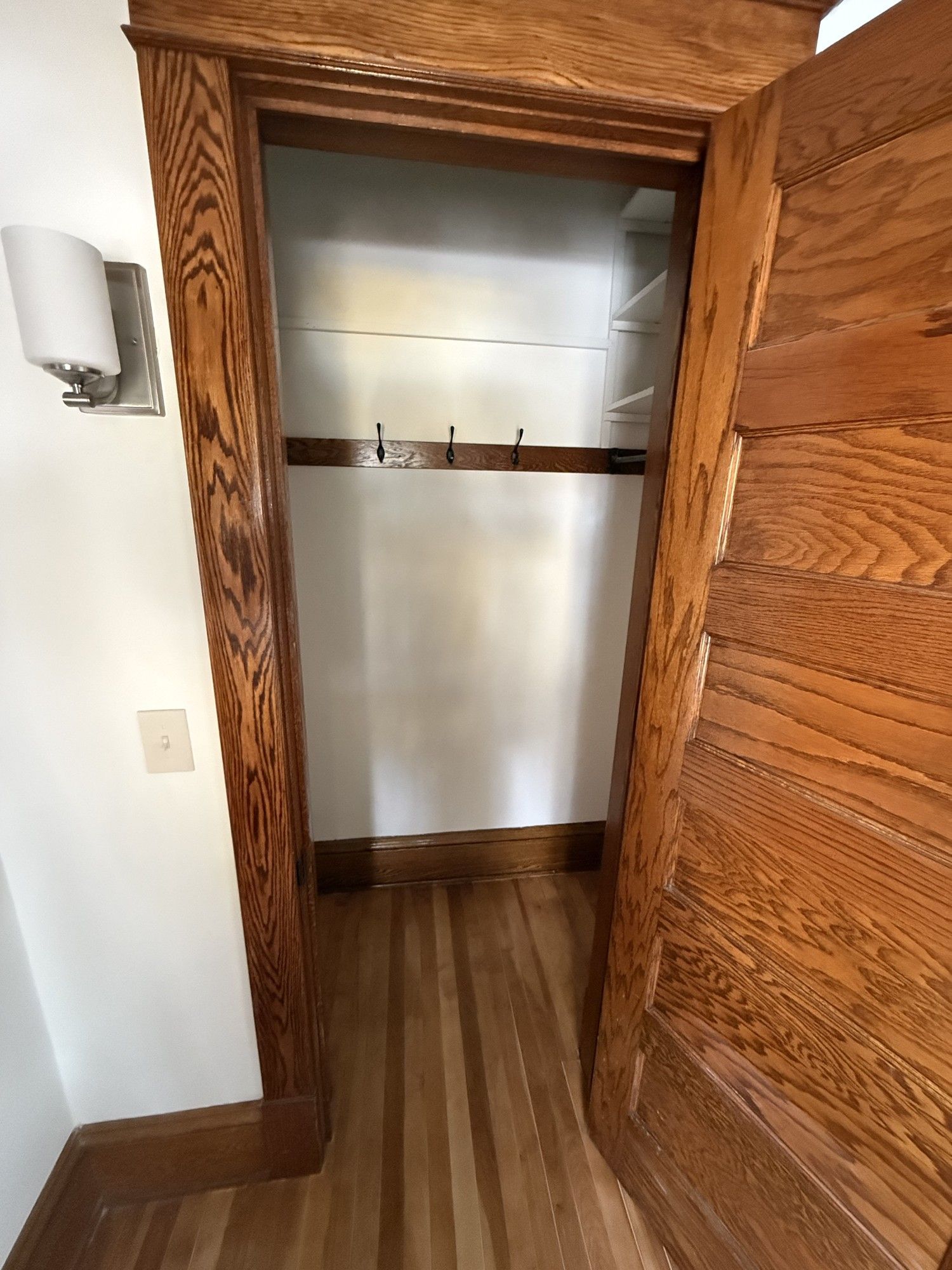 Open closet with wood trim and metal rod in a hallway
