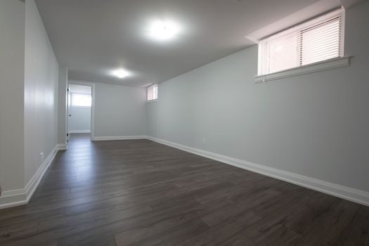 Empty modern room with gray walls, dark wood floor, and small high windows