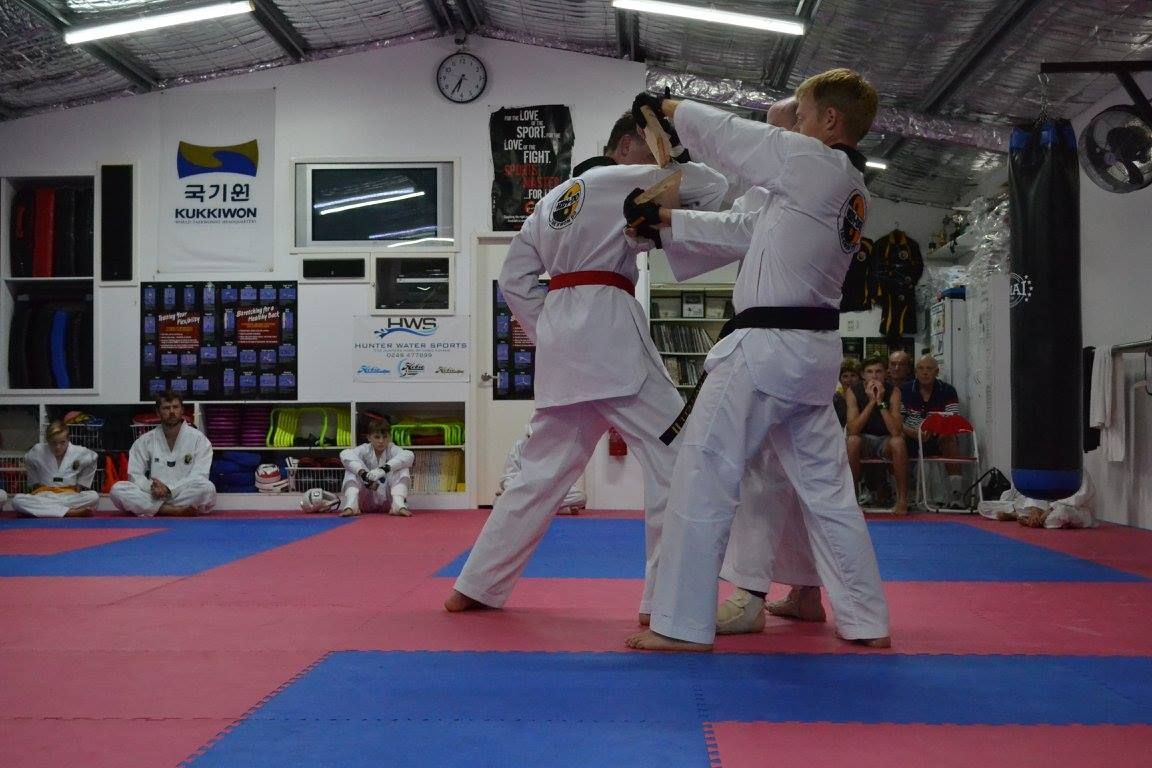 A Man Breaking a Wooden Board with his Elbow — Him-Do Tae Kwon Do Academy In Salamander Bay, NSW