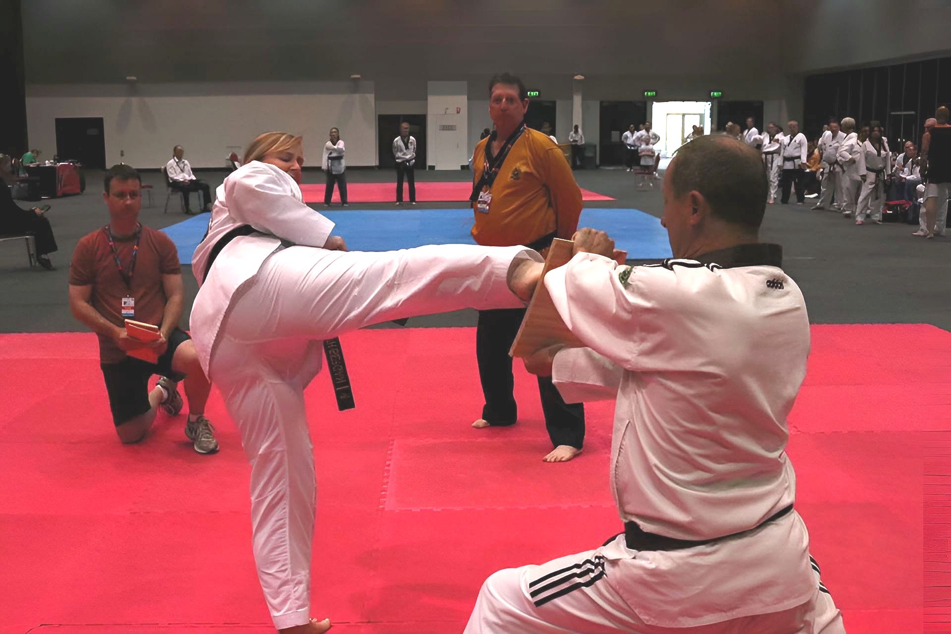 Woman Kicking a Wooden Board Held by a Man — Him-Do Tae Kwon Do Academy In Salamander Bay, NSW