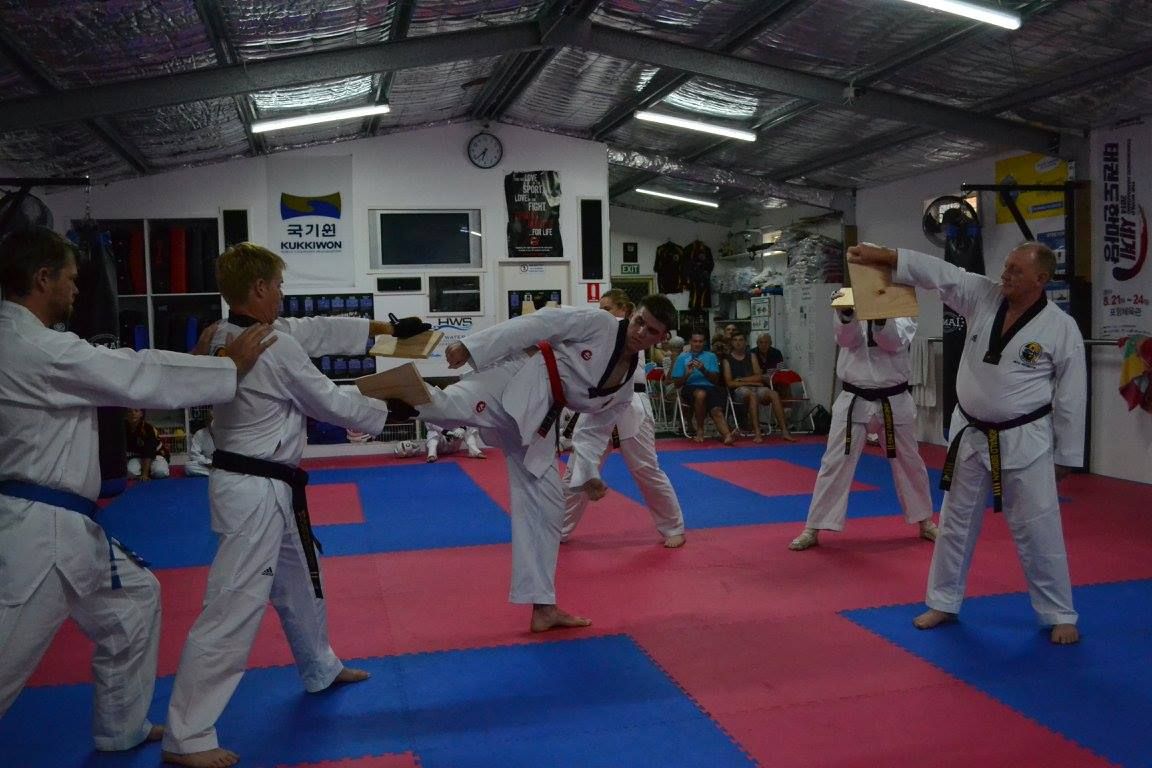 A Group of People Are Practicing Breaking Boards in a Gym — Him-Do Tae Kwon Do Academy In Salamander Bay, NSW