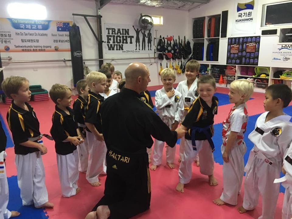 Man Kneeling, Shaking Hands with Class of Martial Artists — Him-Do Tae Kwon Do Academy In Salamander Bay, NSW