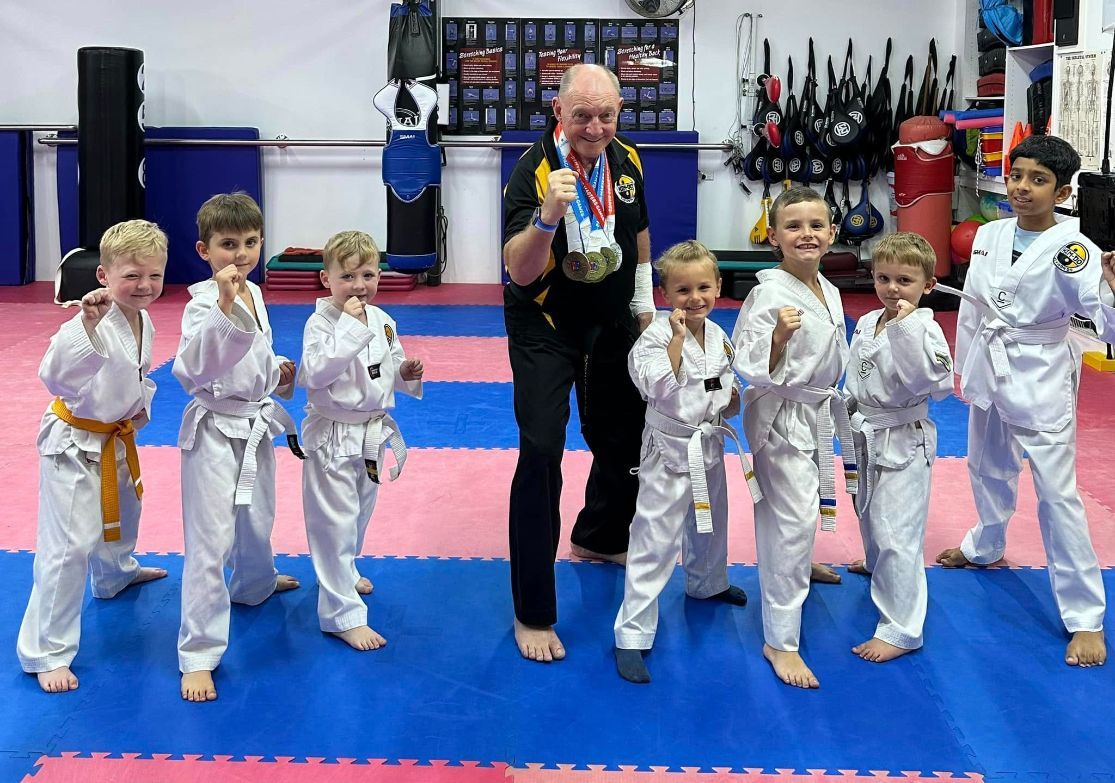 A Man is Standing Next to a Group of Young Boys in Karate Uniforms — Him-Do Tae Kwon Do Academy In Salamander Bay, NSW