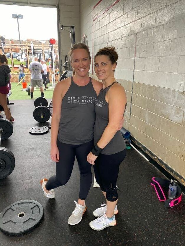 Two women are standing next to each other in a gym.