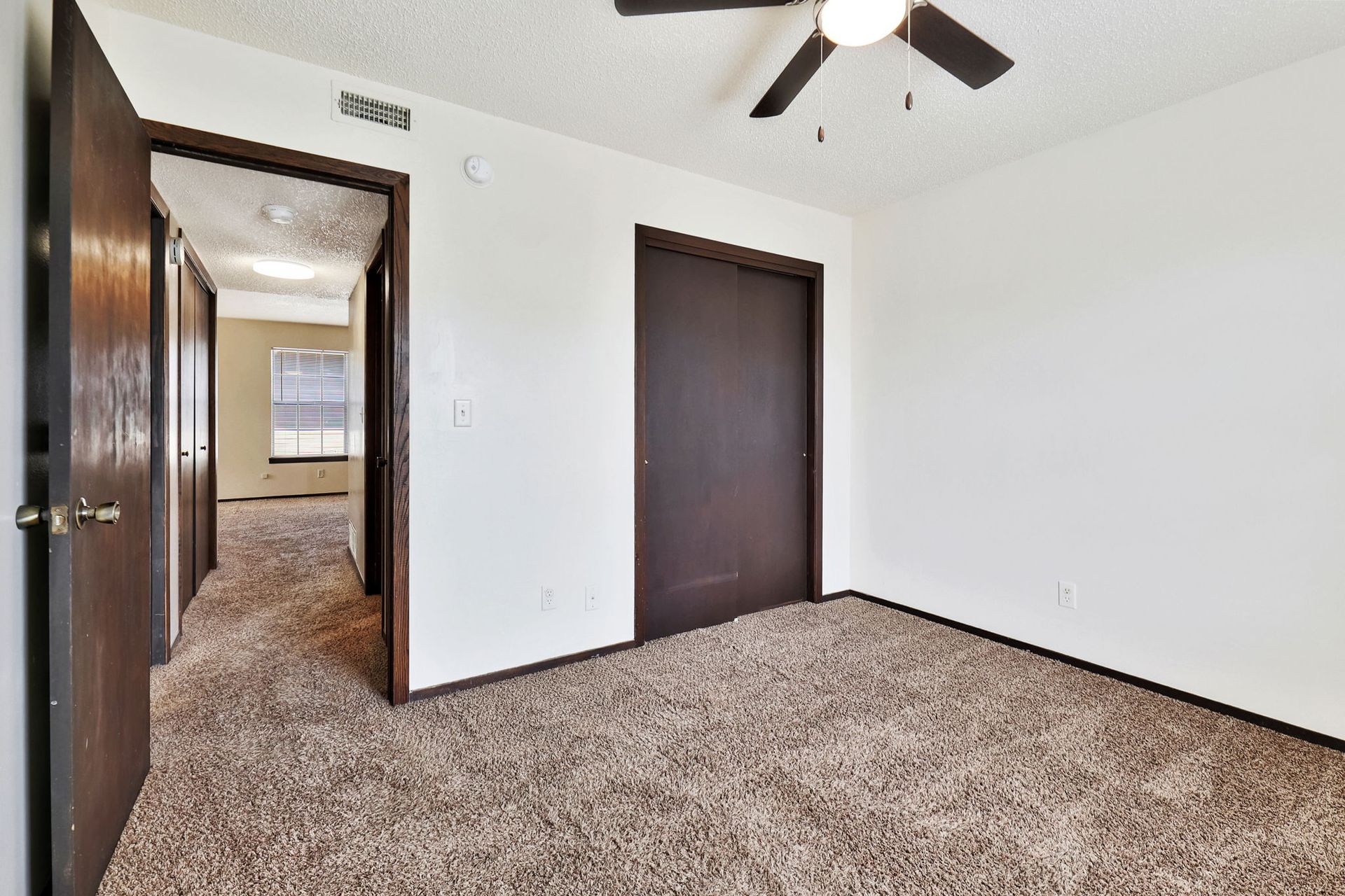 An empty bedroom with a ceiling fan and a closet.