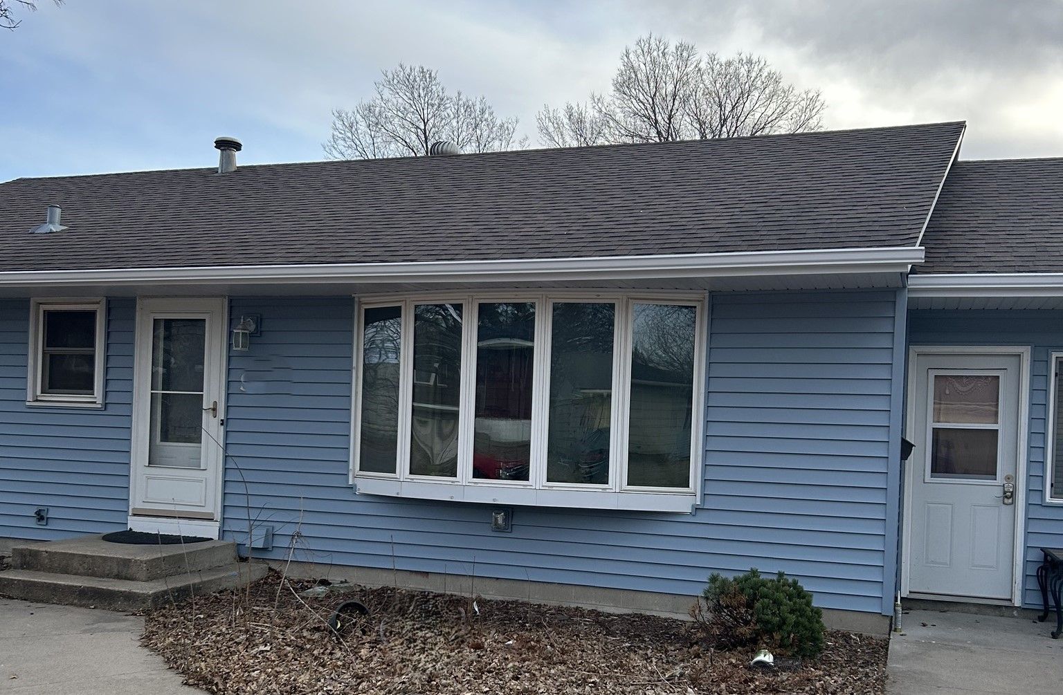 Blue single-story house with a patterned shingle roof, white trim, and front doors on both sides