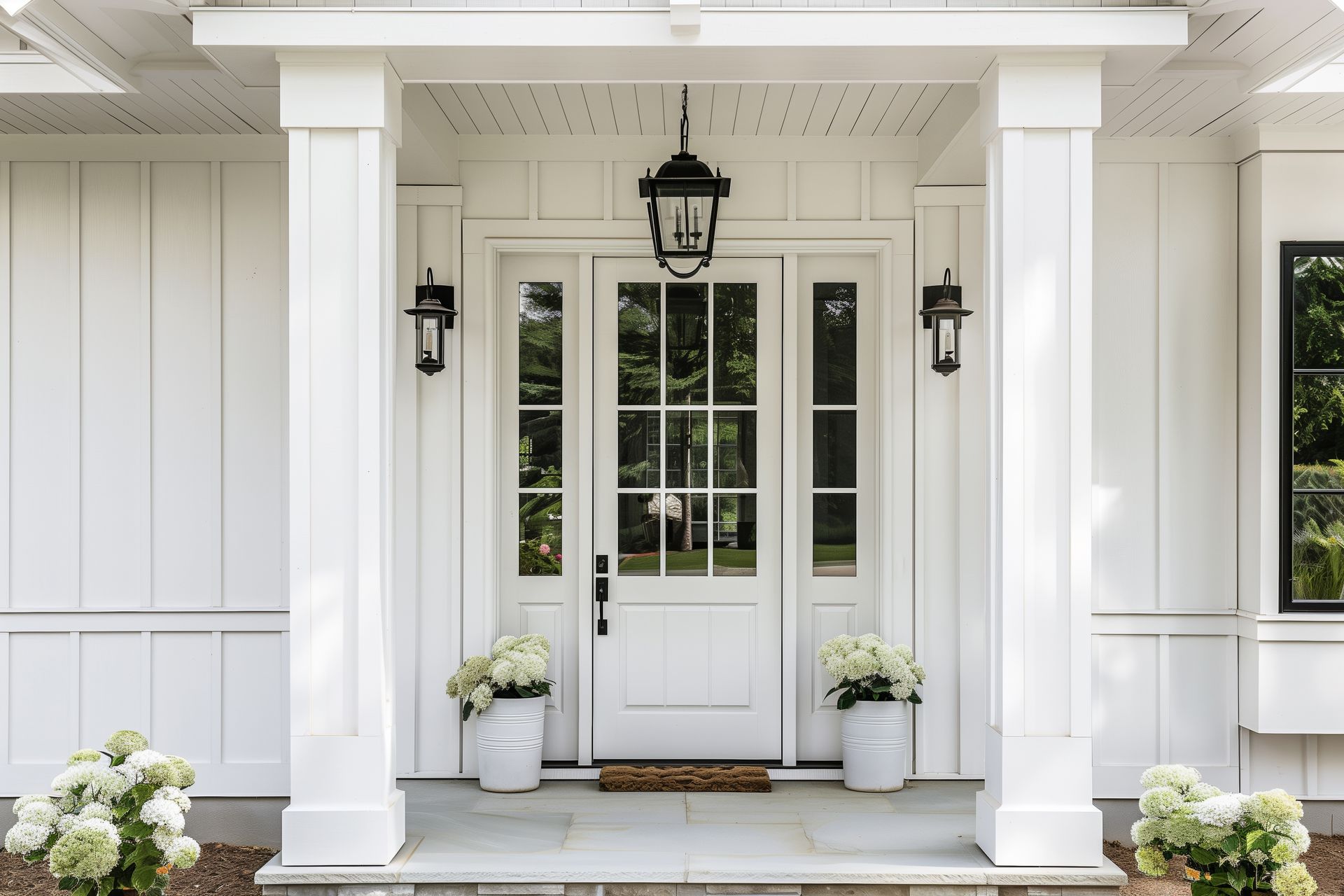 White farmhouse-style front porch with glass door, columns, and potted flowers. White farmhouse-style front porch with glass door, columns, and potted flowers.