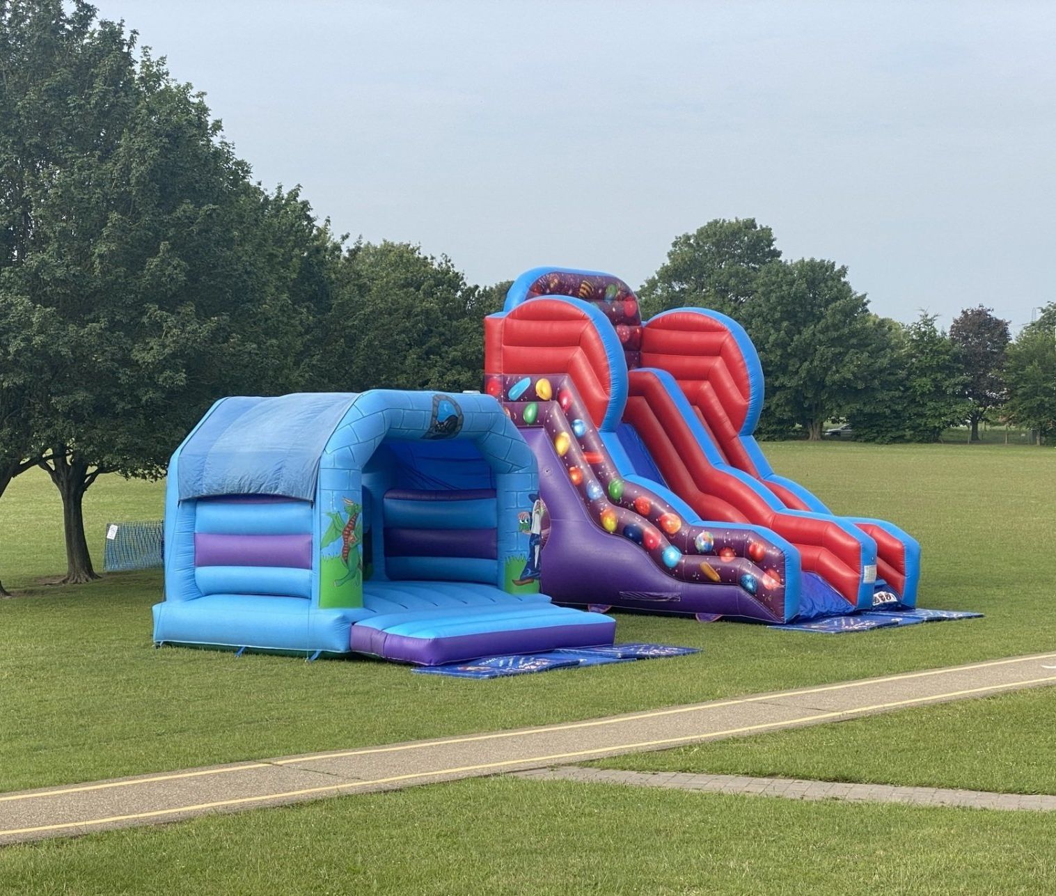 blue bouncy castle and multi colour slide on a school field. Anchored securely on a calm day.