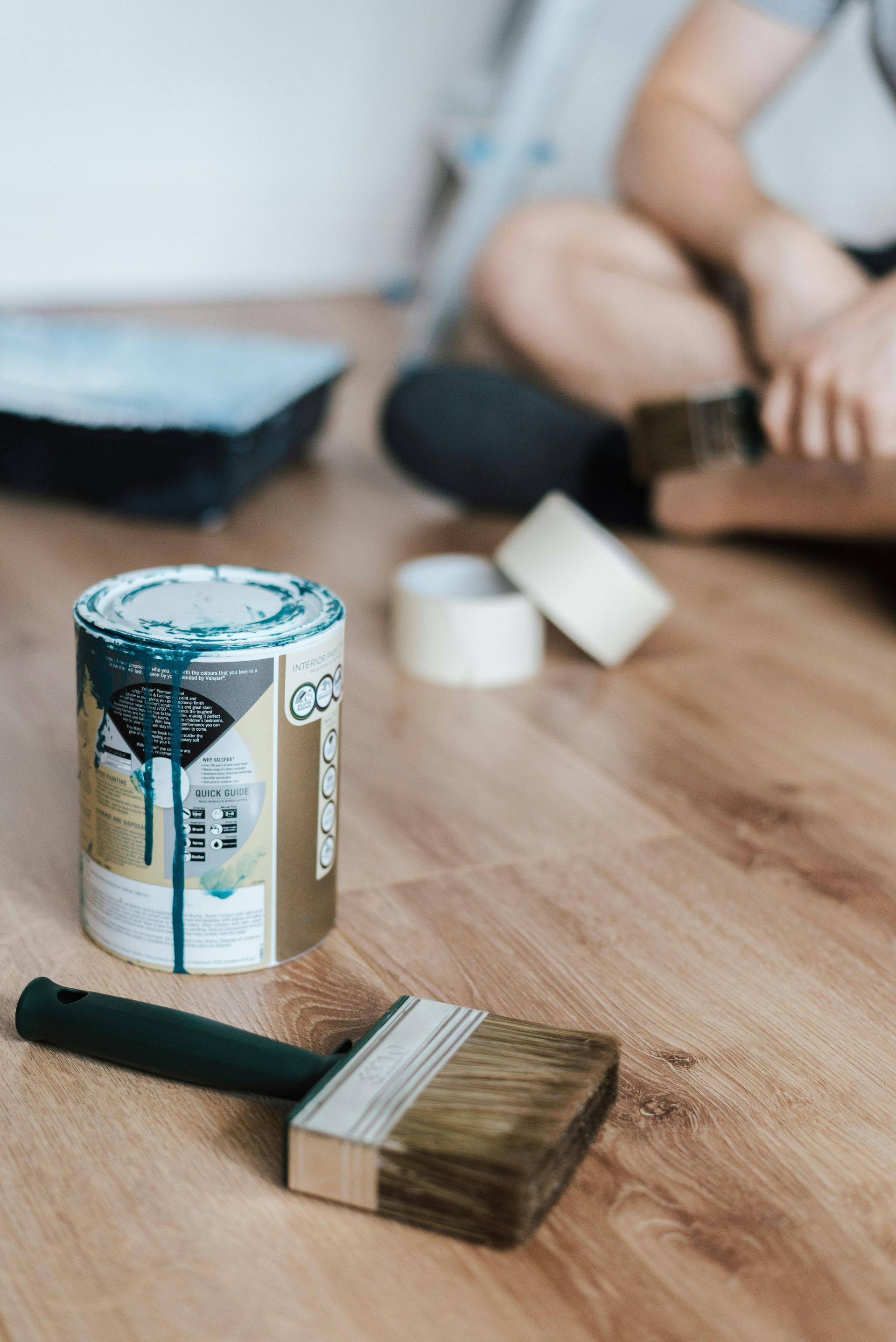 A can of paint and a brush are on the floor.