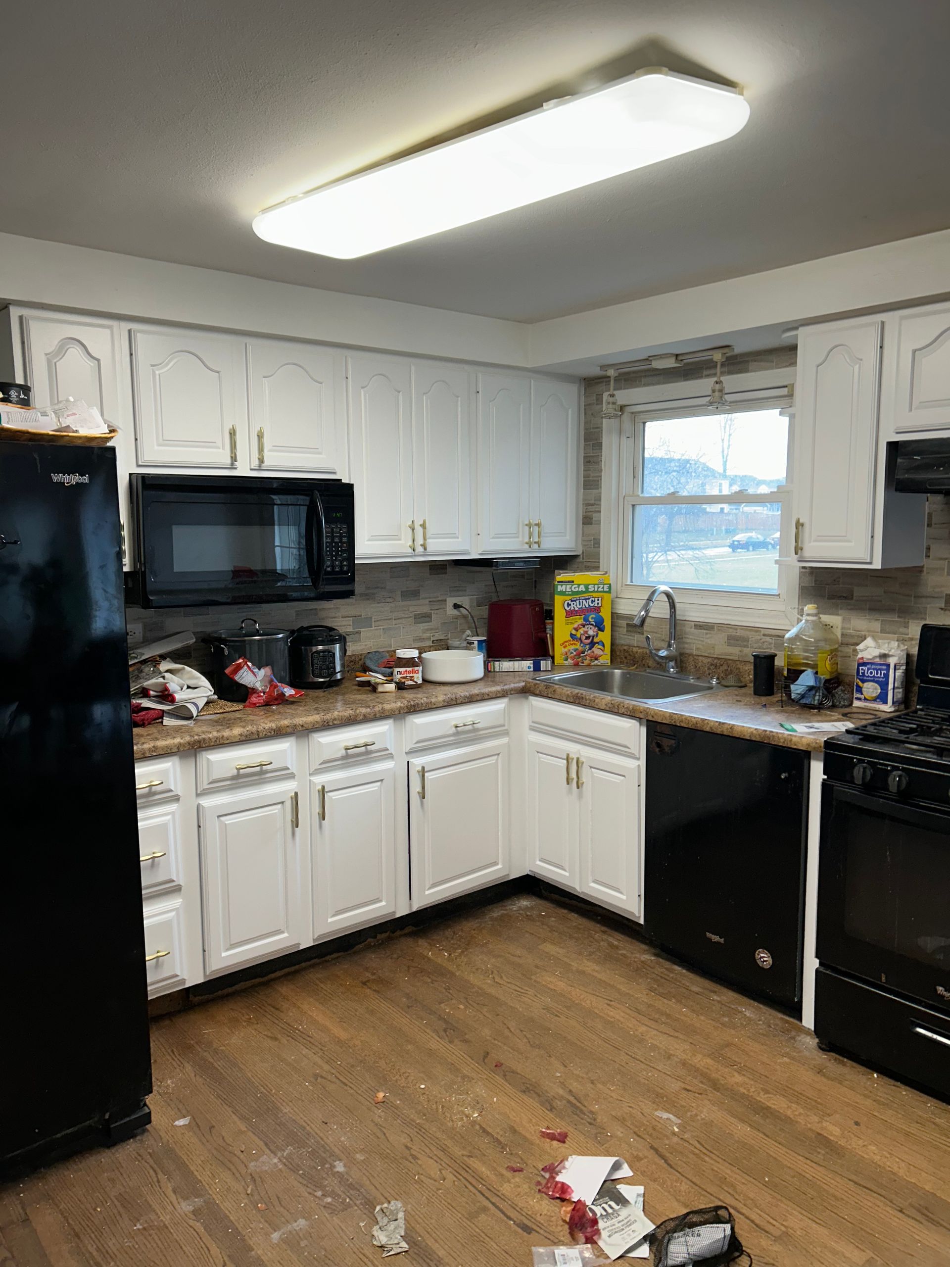 Kitchen with white cabinets, black appliances, and a light-colored wood floor.
