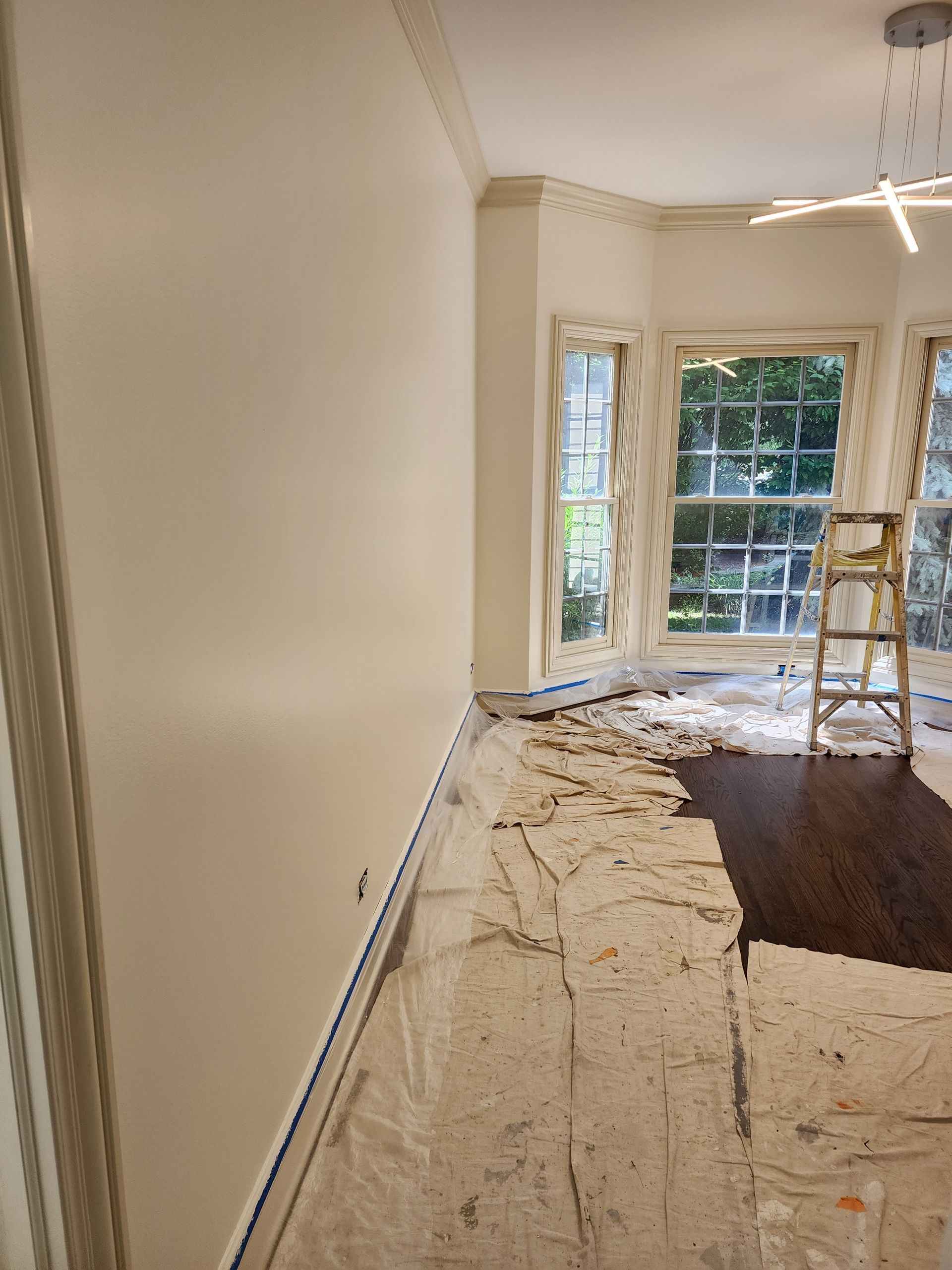 An empty room with a ladder on the floor and a window.