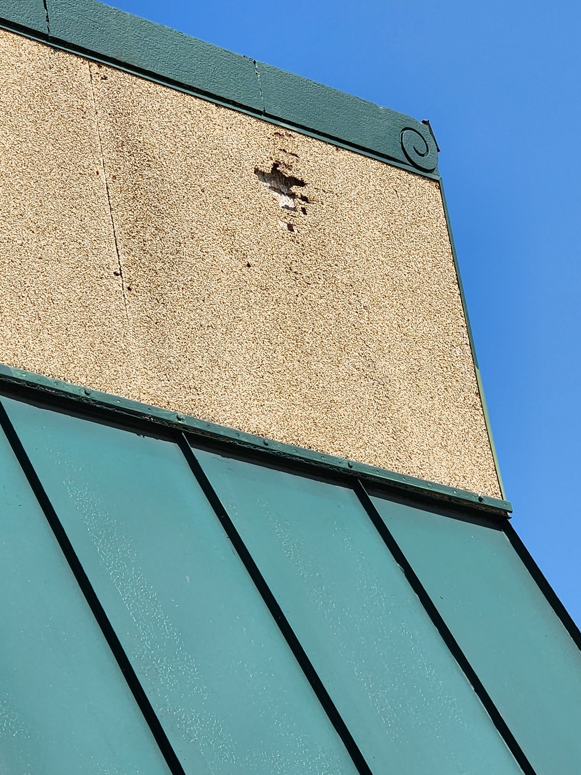 A building with a green roof and a blue sky in the background