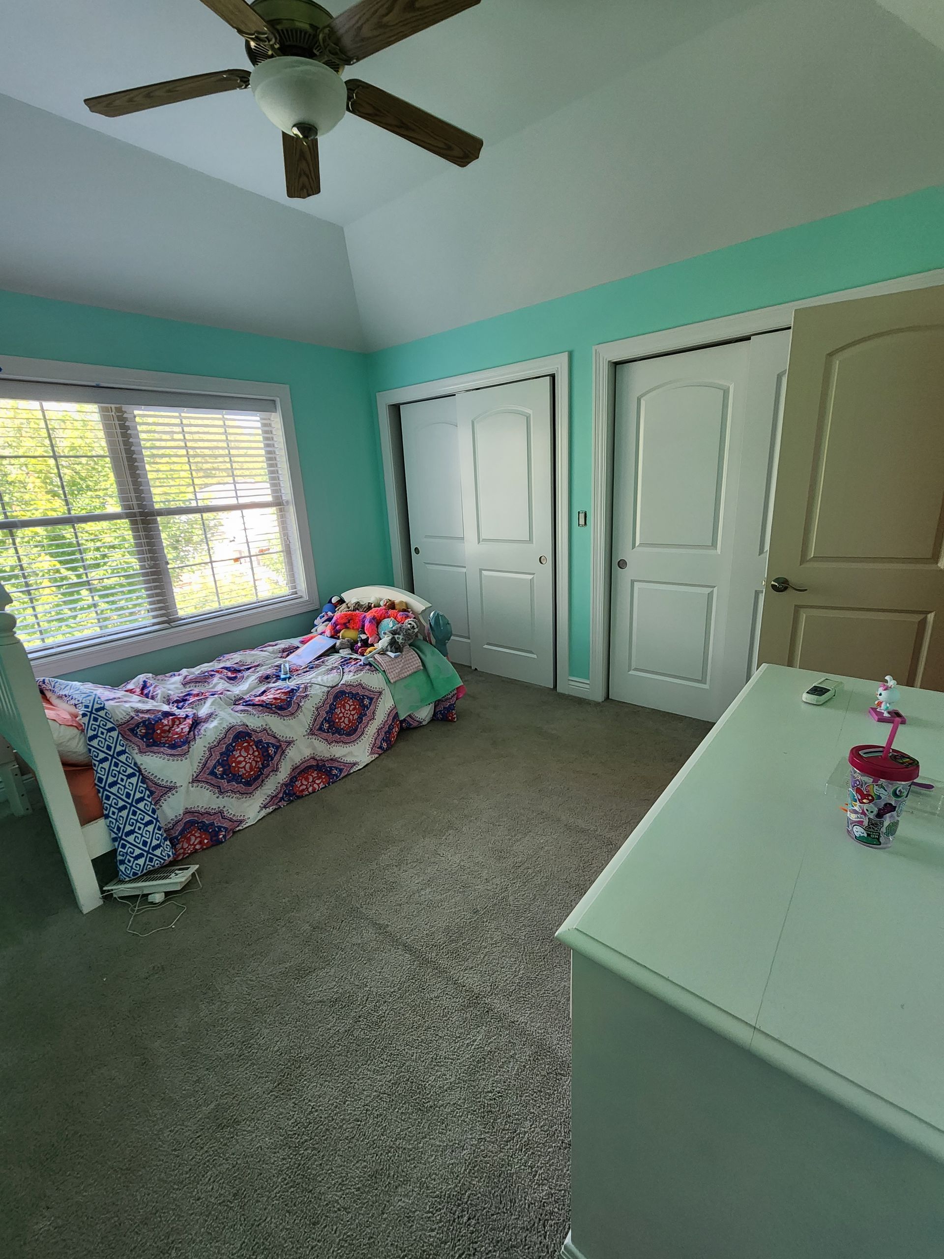 A bedroom with a bed , dresser , and ceiling fan.
