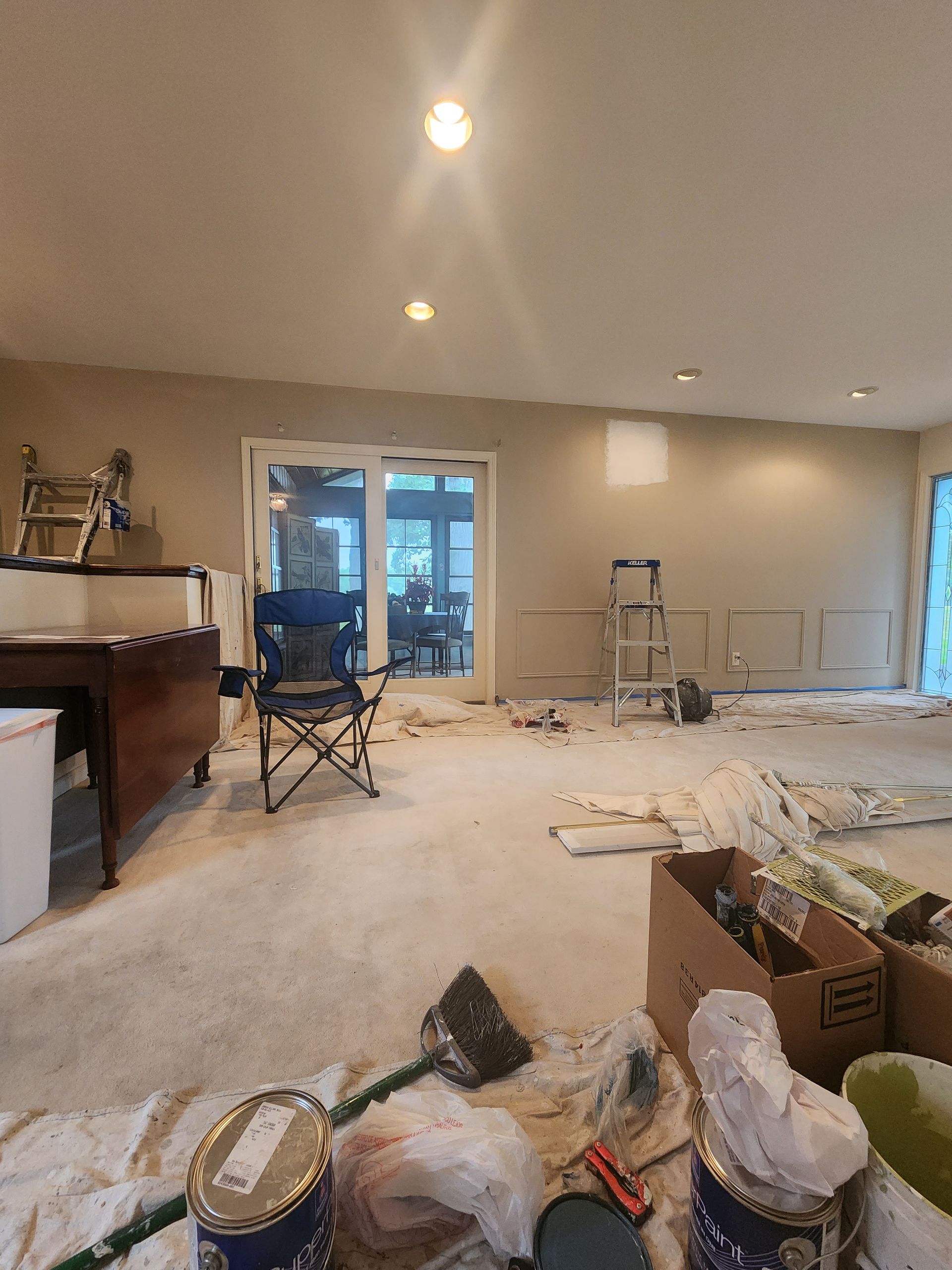 A room that is being painted with buckets of paint on the floor.