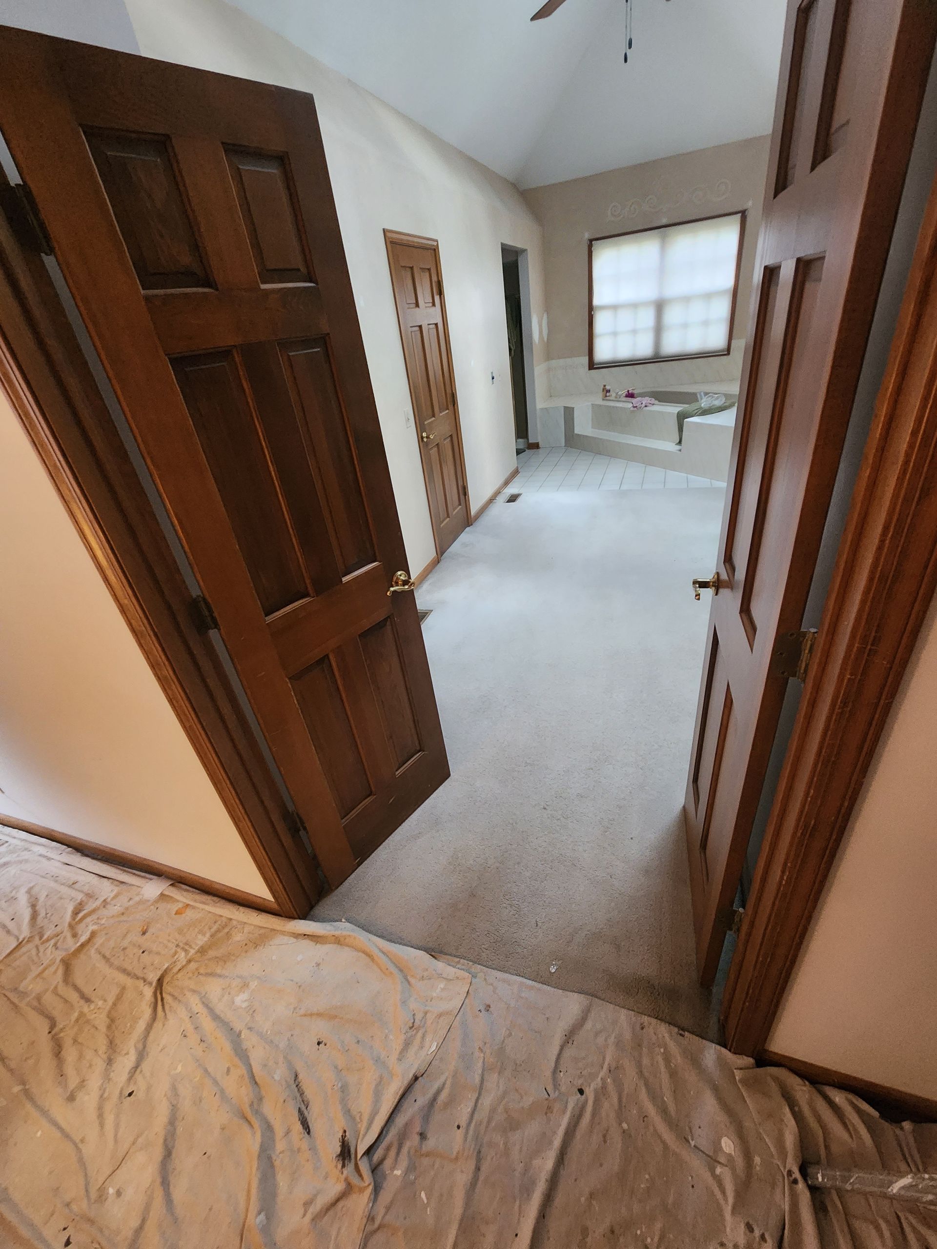 A hallway with wooden doors and a ceiling fan