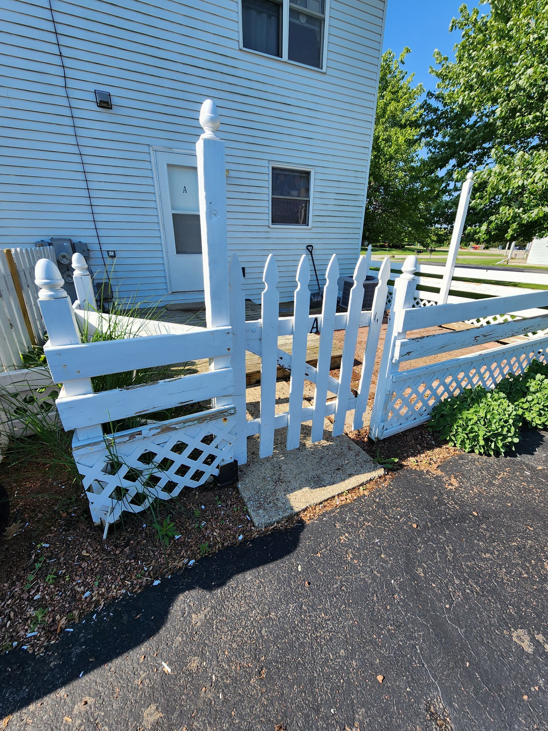 A white picket fence is in front of a white house.