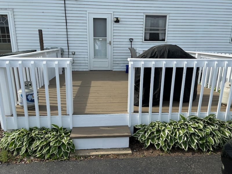 A white house with a wooden deck and stairs