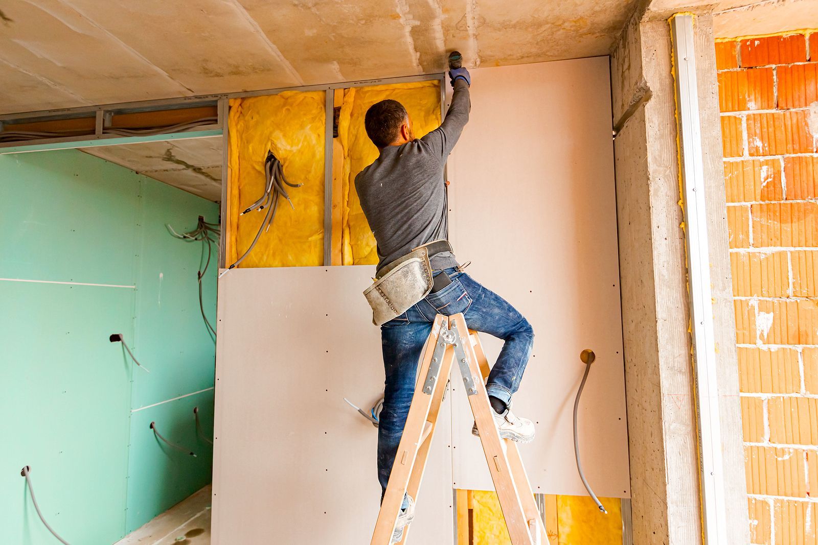 man on ladder next to wall