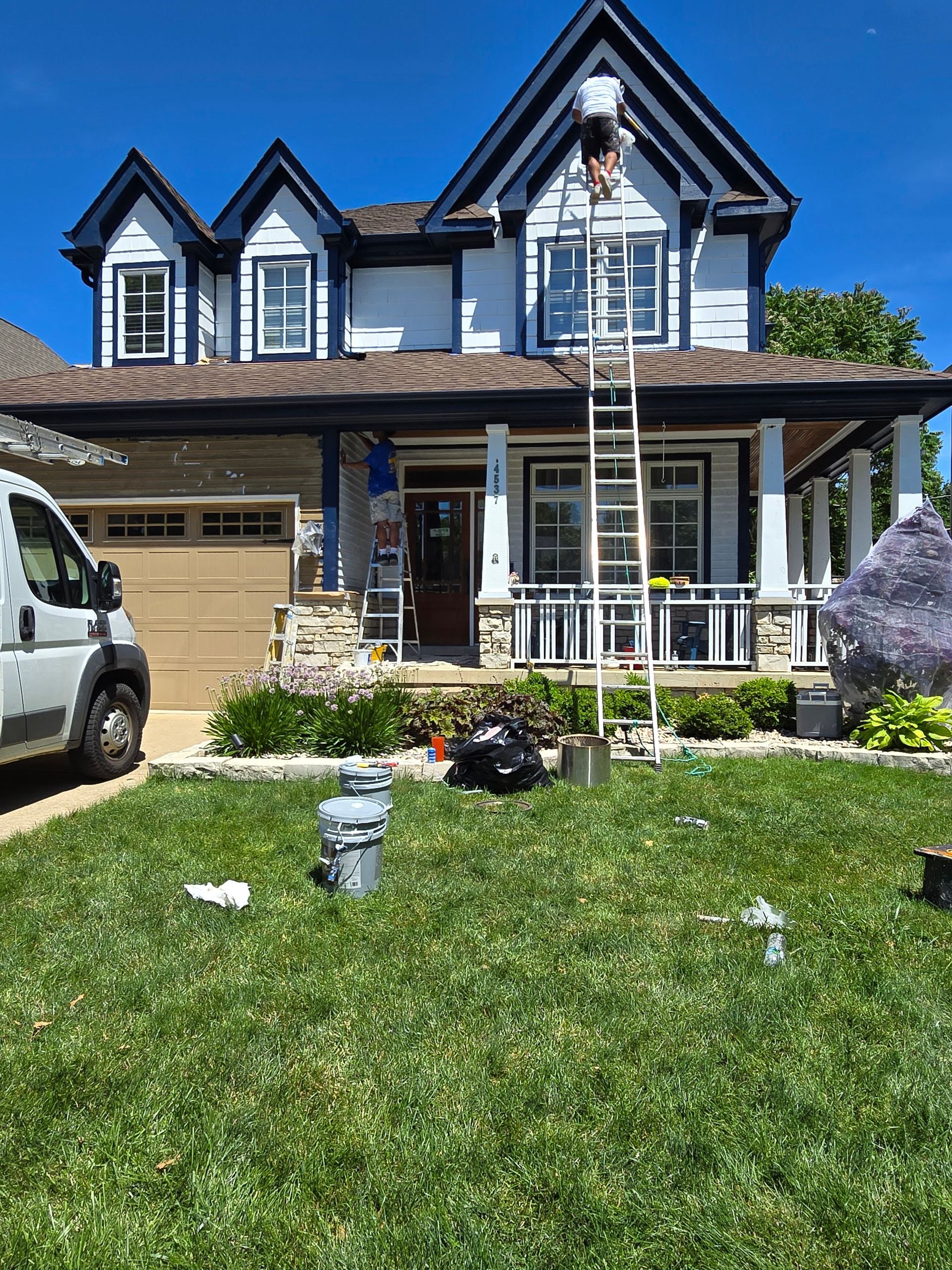 A white van is parked in front of a house being painted.