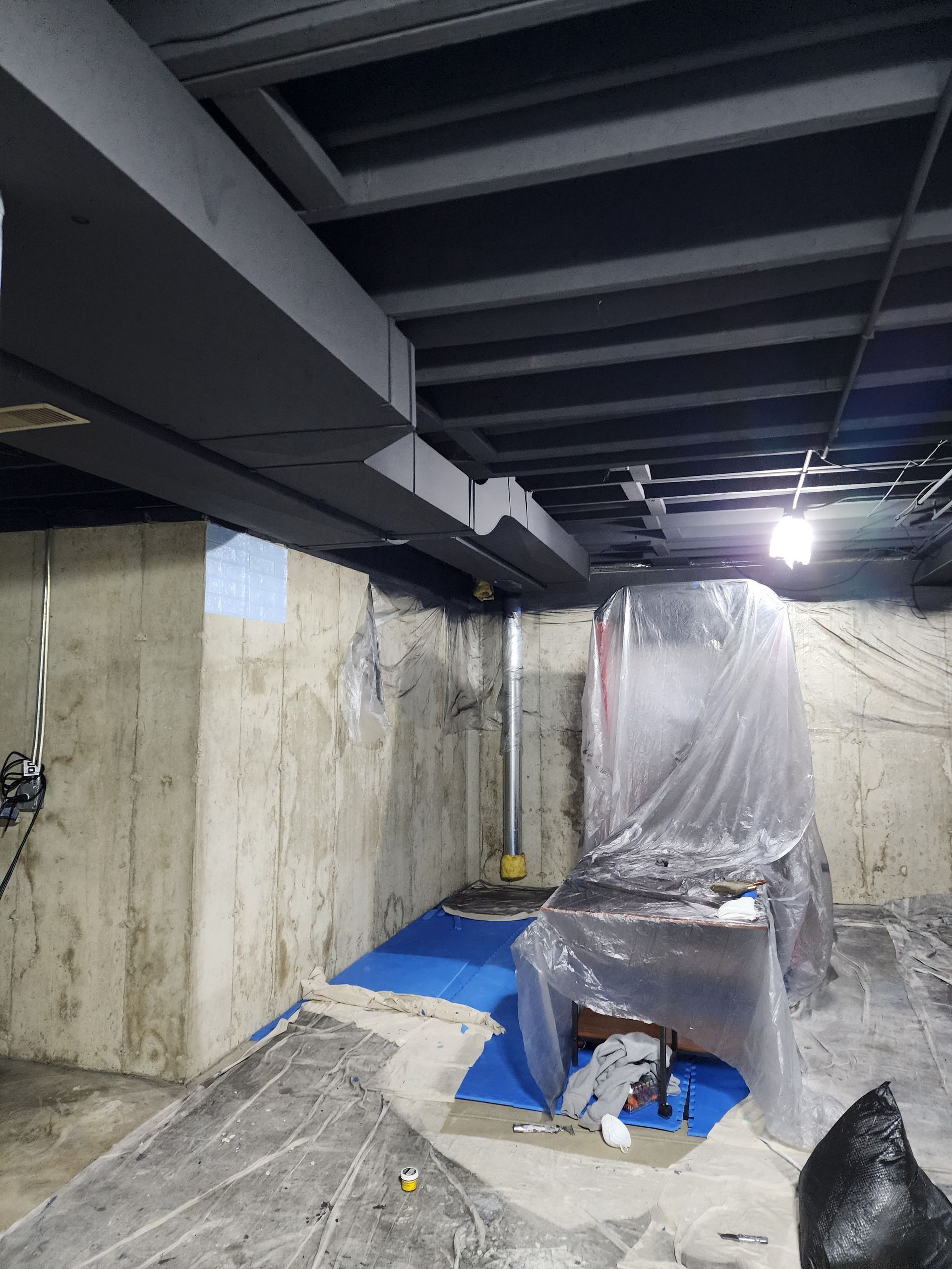 A basement with a ceiling that is covered in plastic.