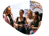 Group of people examining craft, one holding item, in front of a screen.