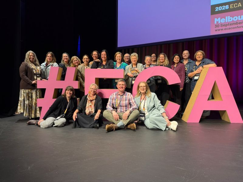 A group of people stand around large letters #ECA