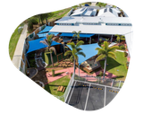 Aerial view of a childcare center with shaded outdoor play areas, green lawns, and parking lot.