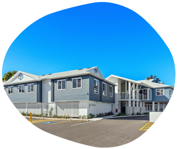 Blue and white multi-unit residential building under a clear, bright blue sky.
