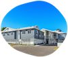 Blue and white two-story building with a parking lot and clear sky in a blue circle.