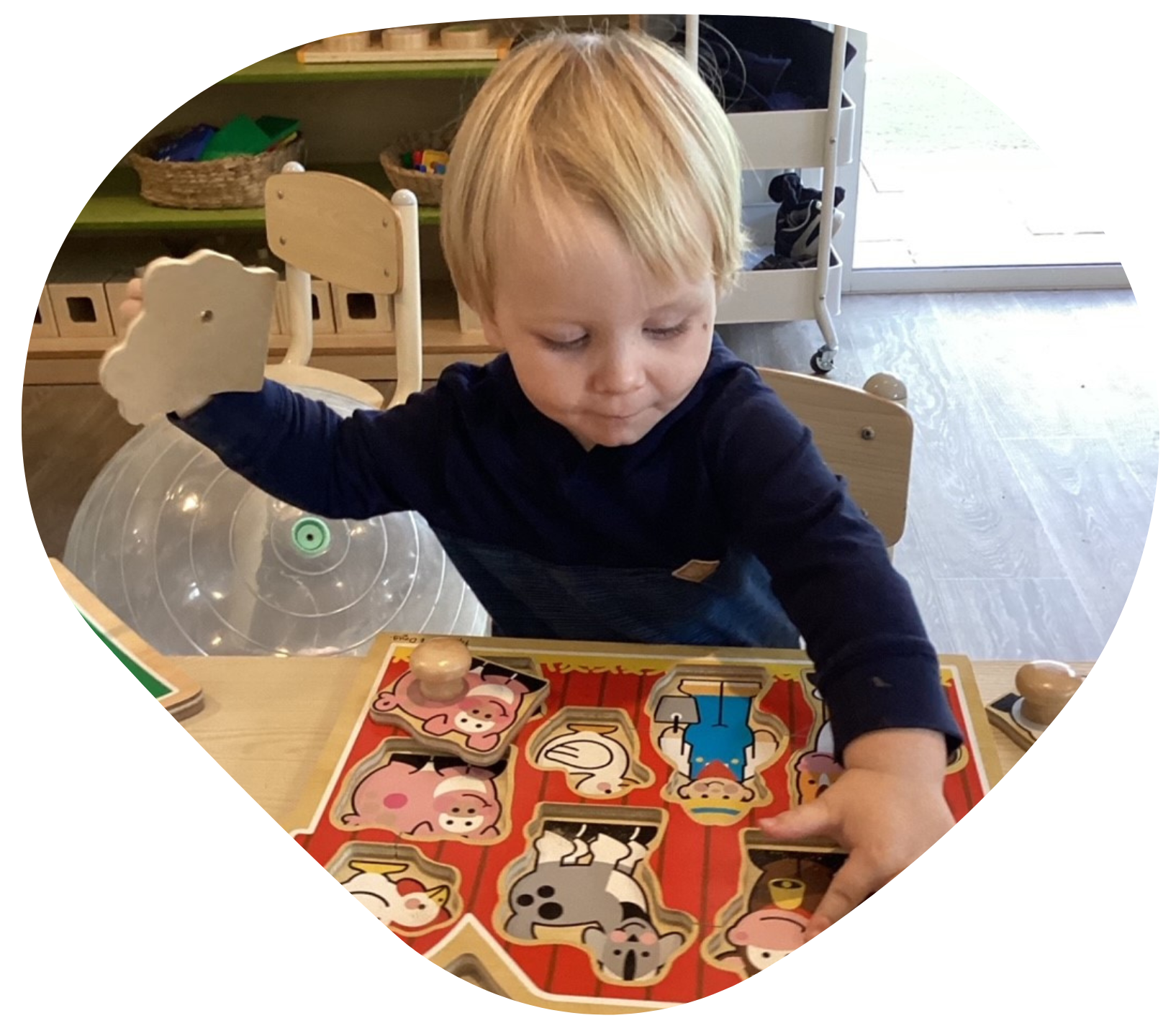 Boy putting together a farm animal puzzle at a table, indoors.