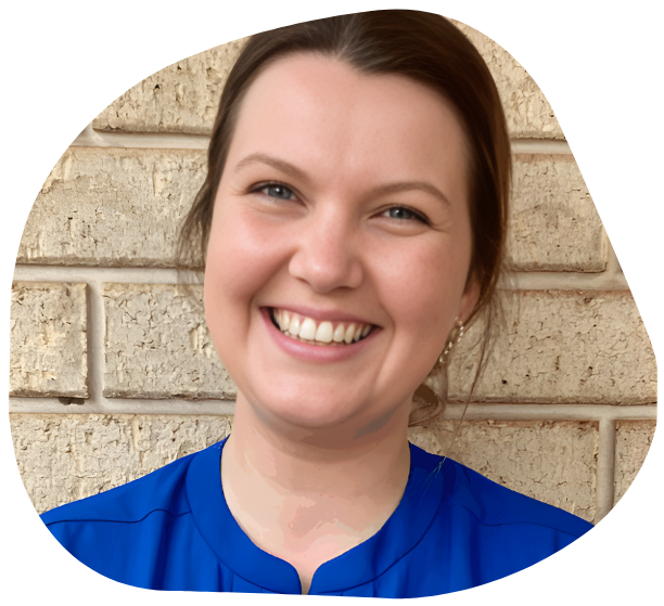 Woman smiling, blue top, in front of a brick wall.