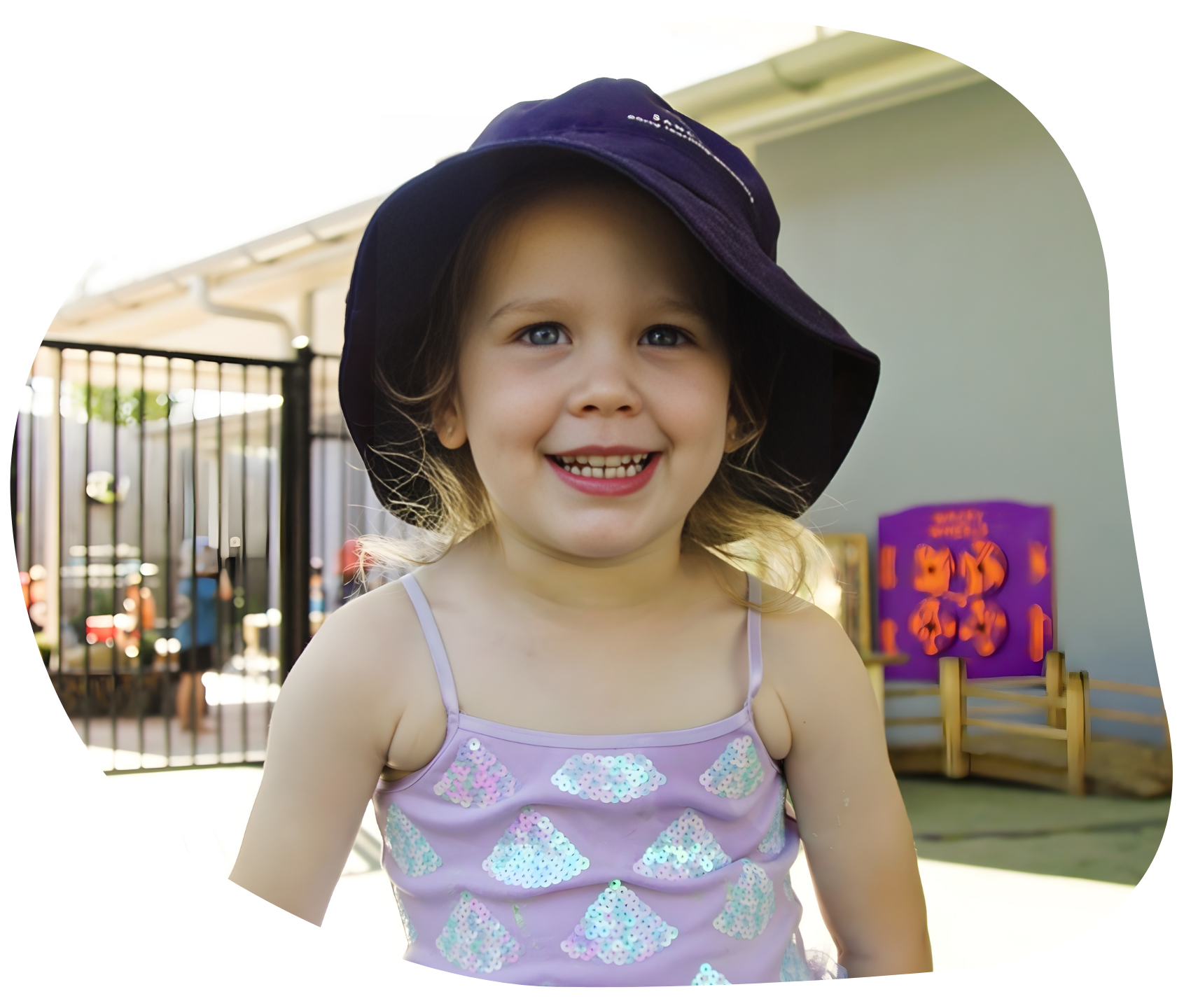 Smiling child wearing a blue hat and light purple tank top.