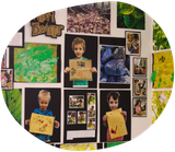 Children's artwork and photos on a wall. One child holds a brown paper drawing.