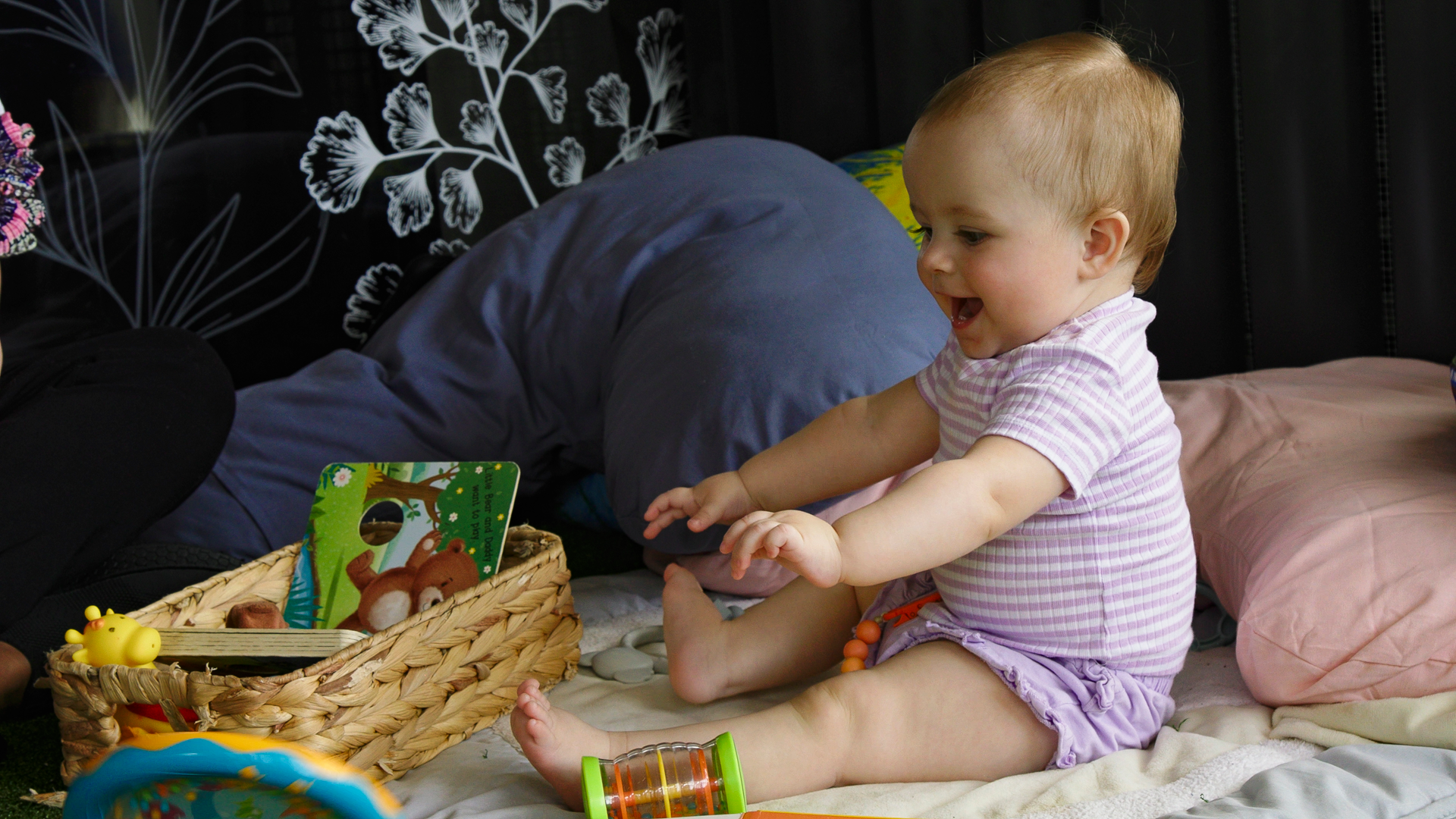 baby playing happily on a mat with books and toys