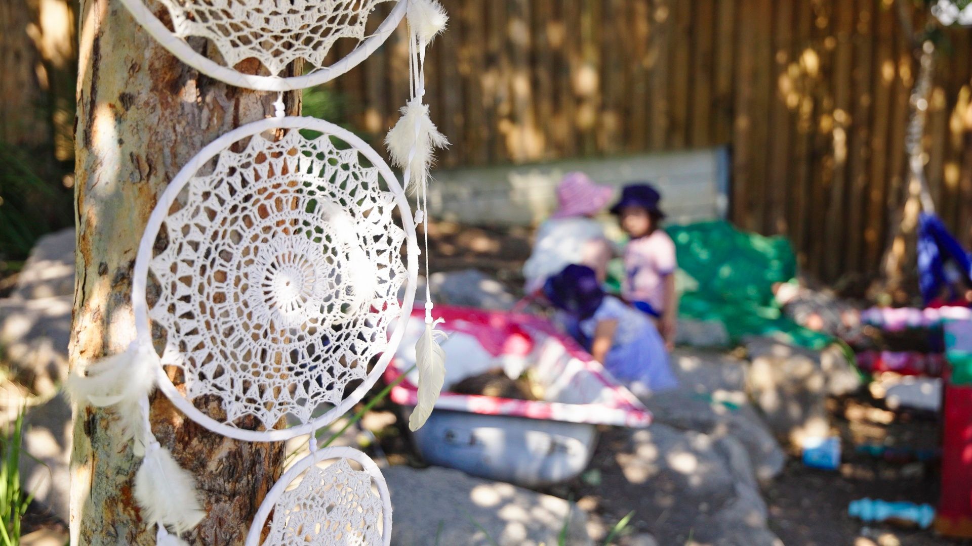 outdoor childcare setting with dreamcatcher and children in the background