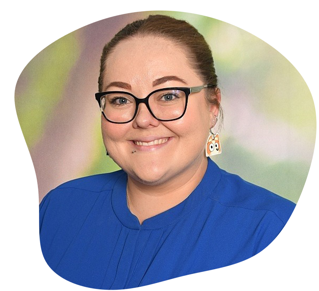Woman with glasses and bun, wearing blue shirt, smiling.